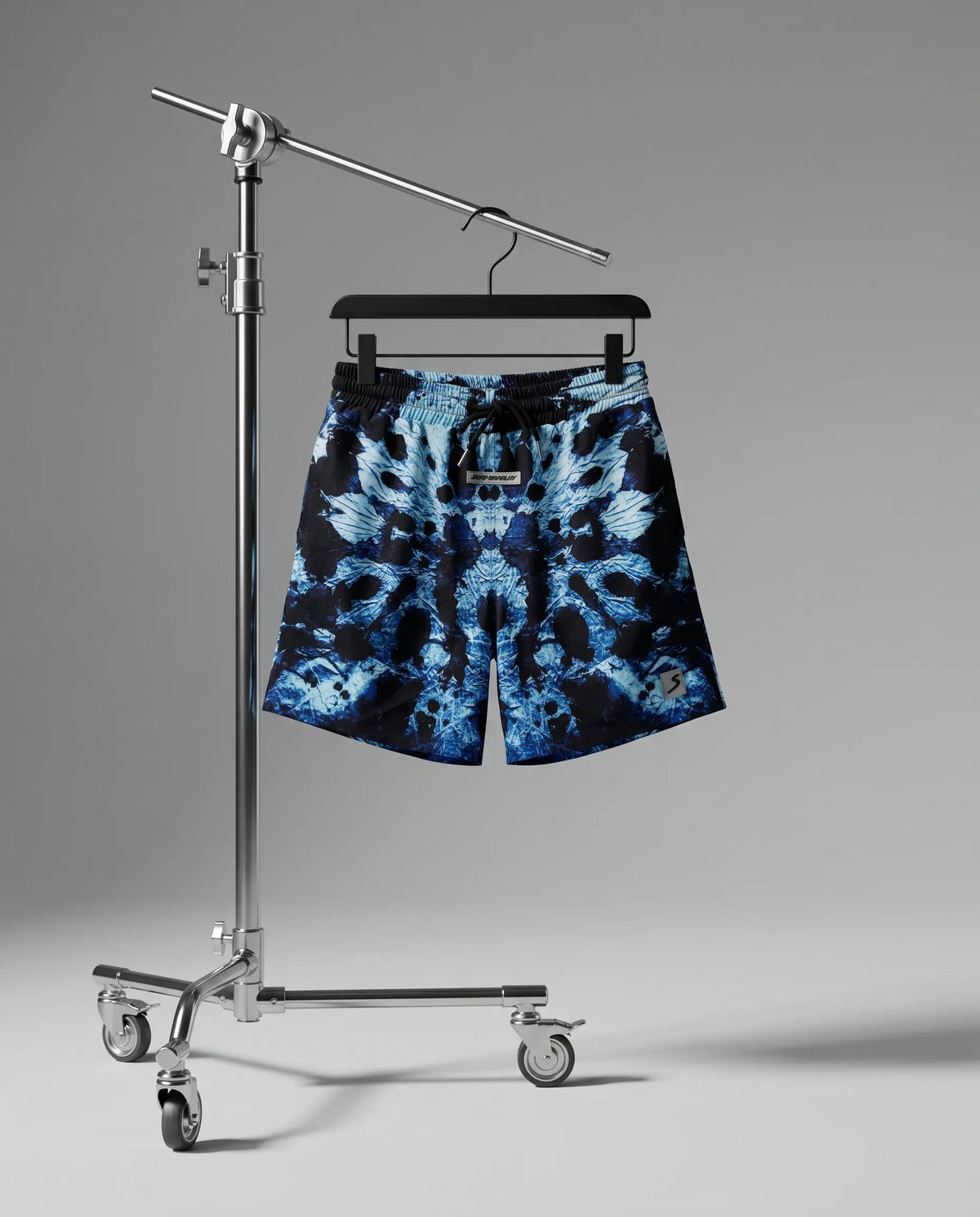 Blue tie-dye shorts on a hanger against a gray background
