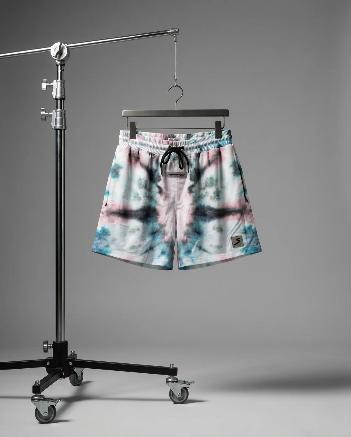 Tie-dye shorts on a hanger against a gray background
