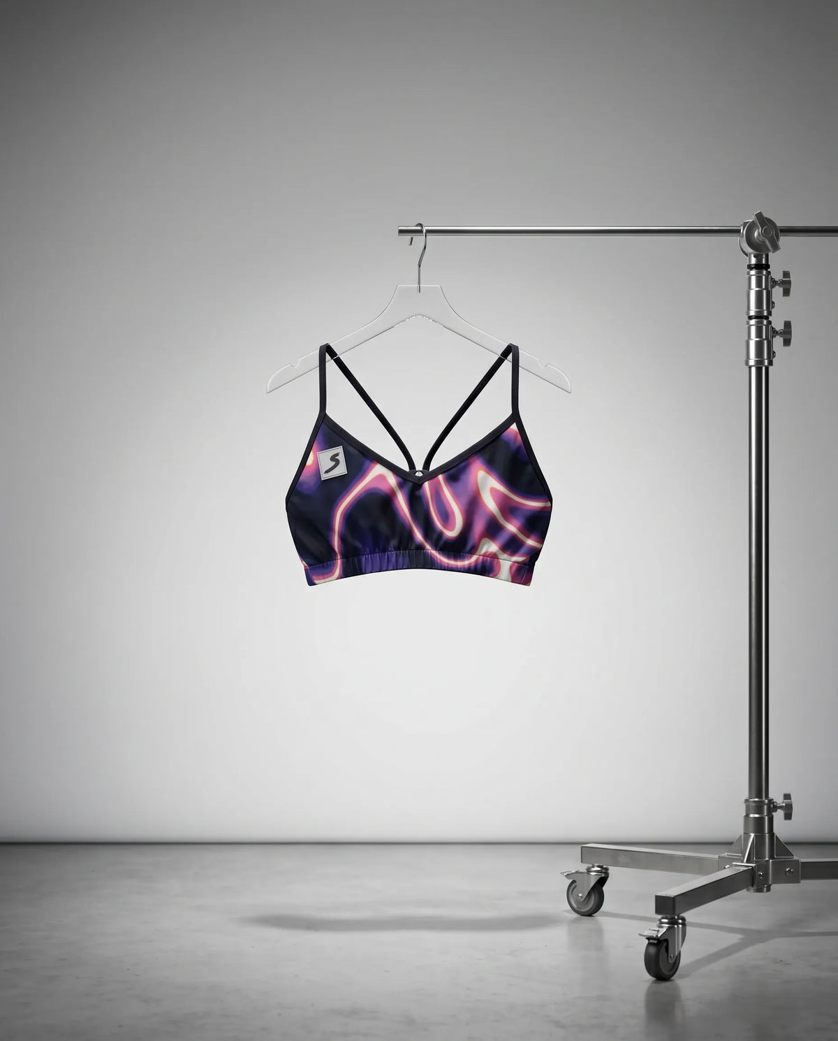 Purple and black sports bra on a hanger against a gray background