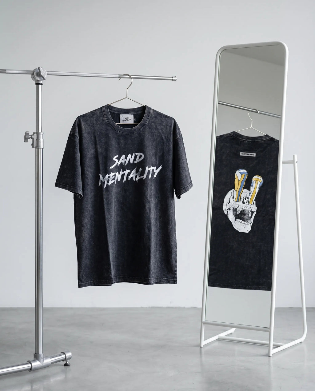 Two black t-shirts with different designs on a rack and mirror.
