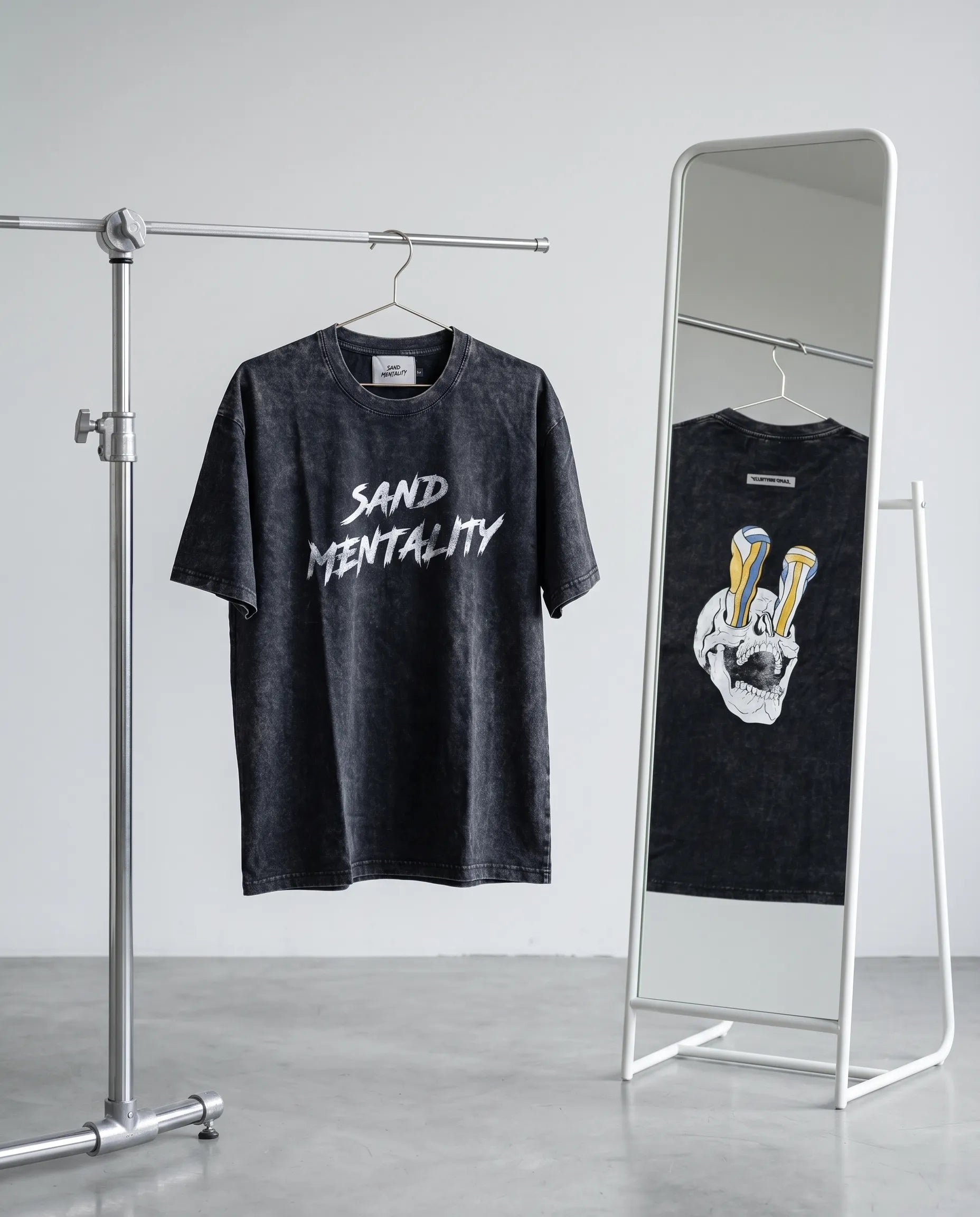 Two black t-shirts with different designs on a rack and mirror.