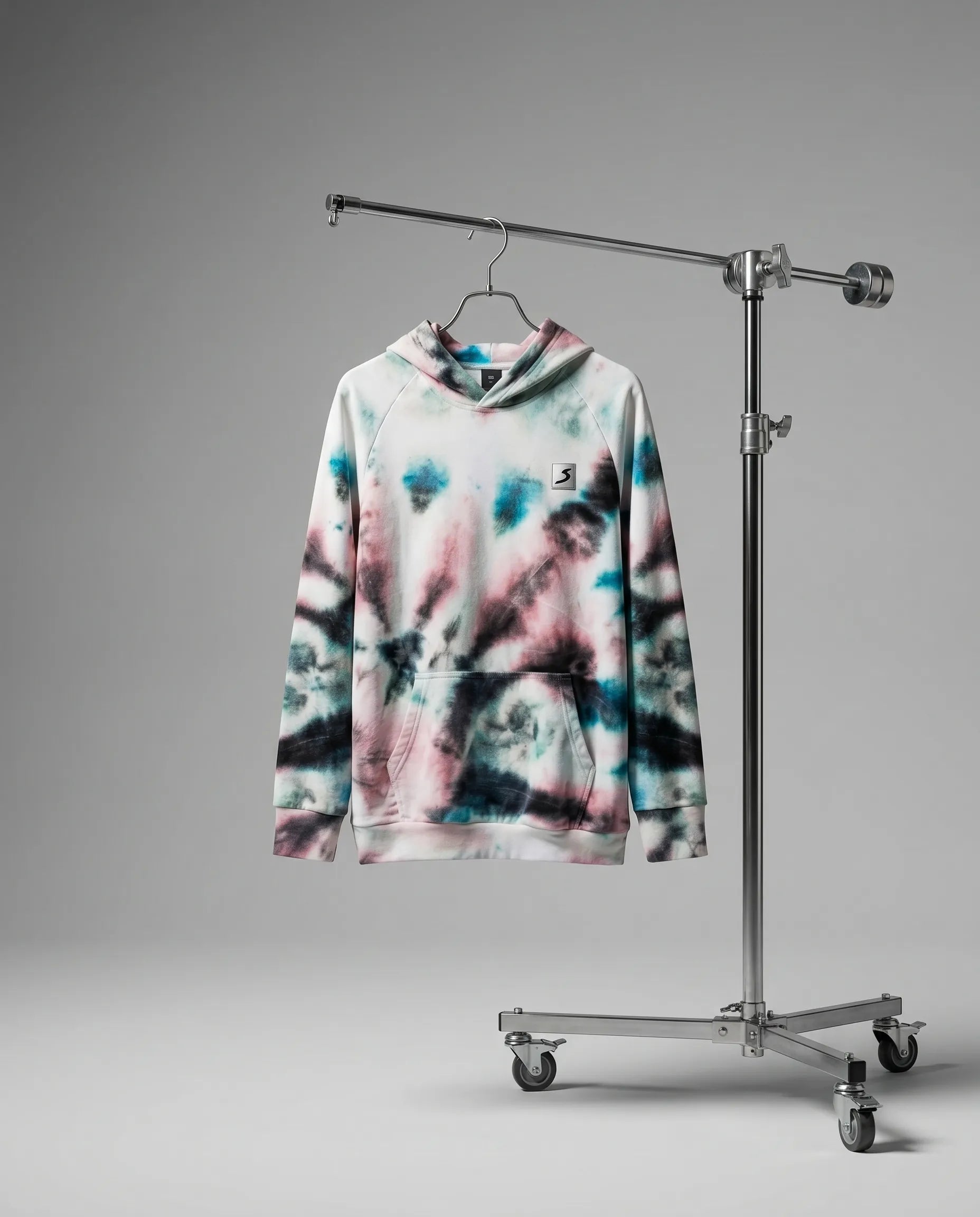Tie-dye hoodie on a hanger attached to a metal stand against a gray background