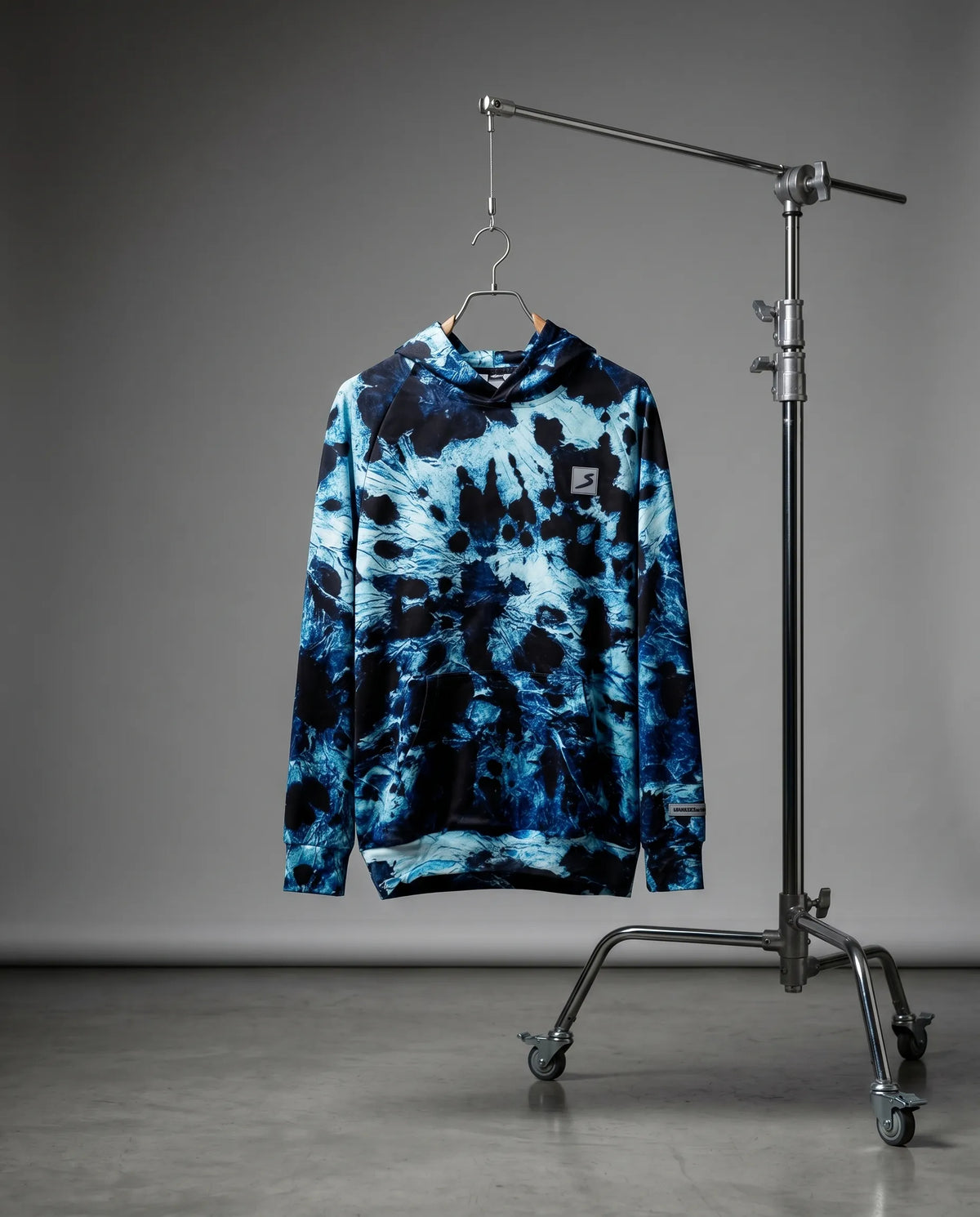 Blue tie-dye hoodie on a hanger against a gray background