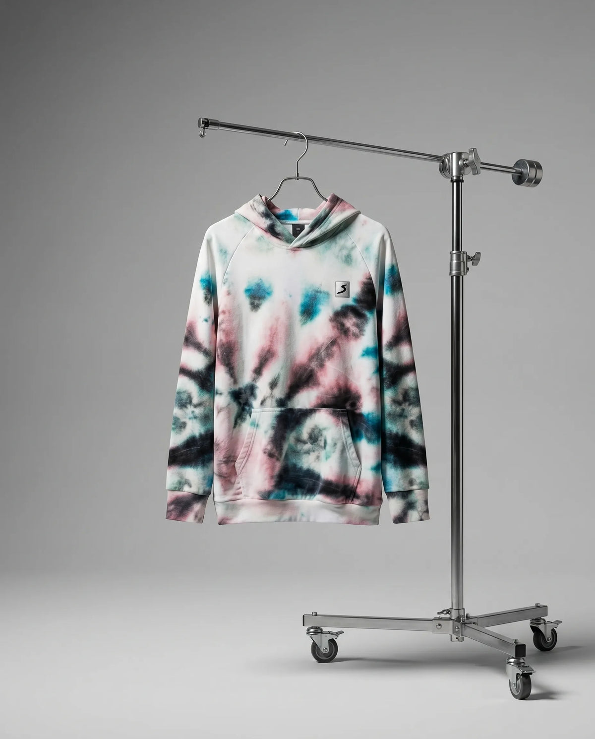 Tie-dye hoodie on a hanger attached to a metal stand against a gray background