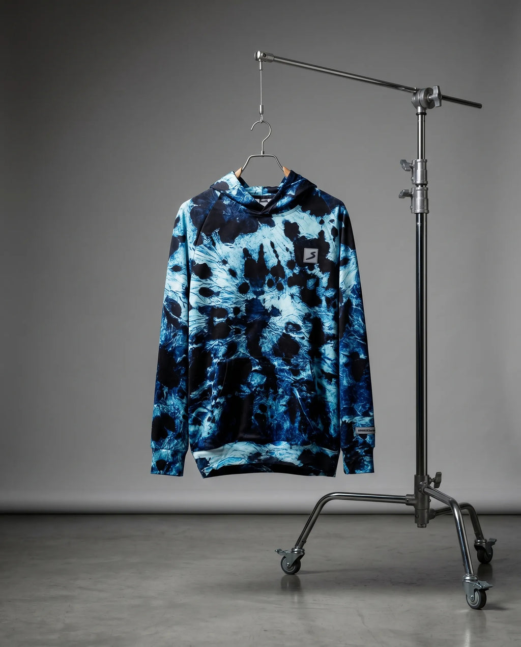 Blue tie-dye hoodie on a hanger against a gray background