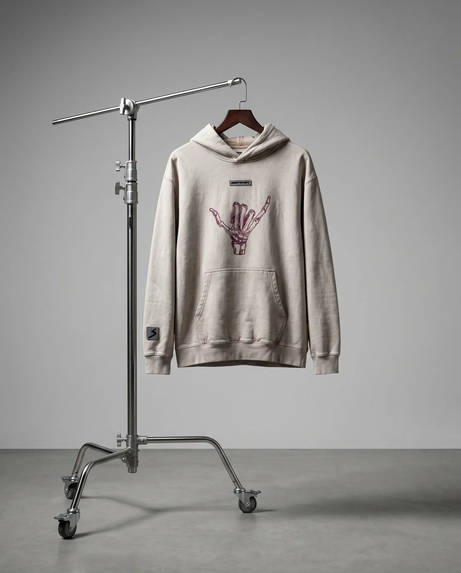 Beige hoodie with a graphic design on a stand against a gray background